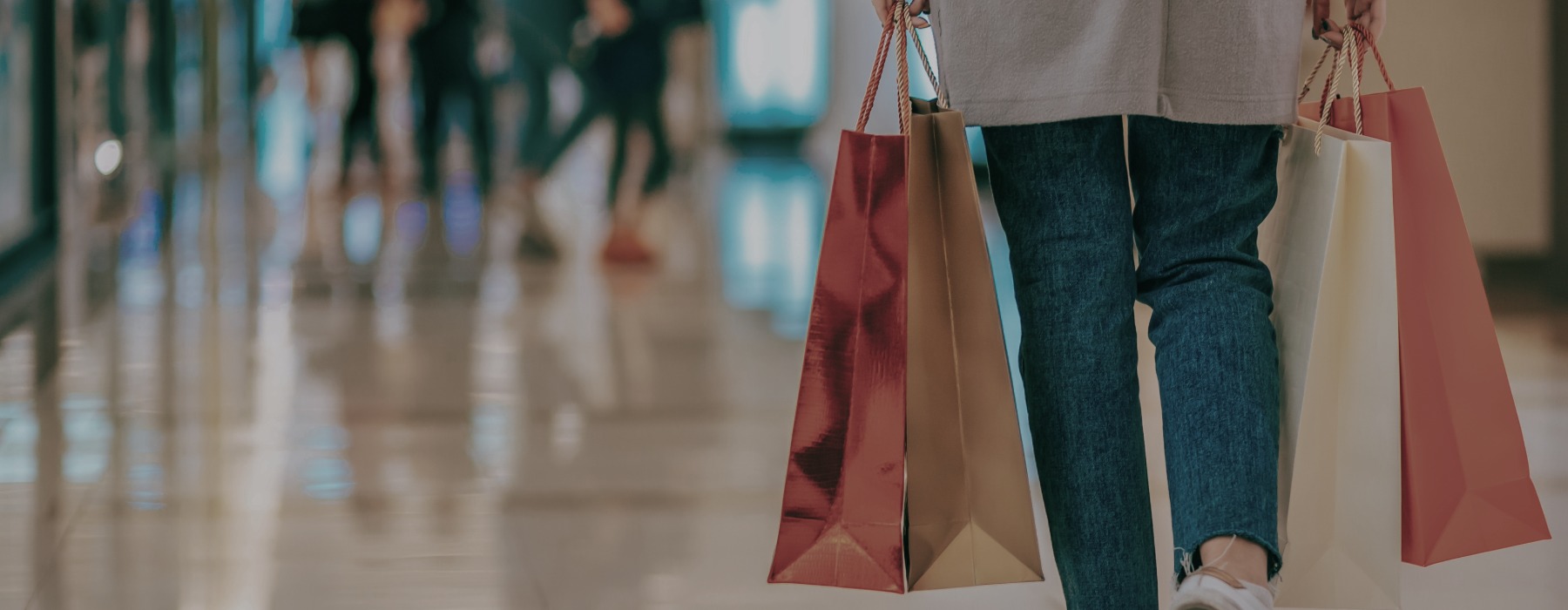 An image of a woman with a shopping back walking in a mall.